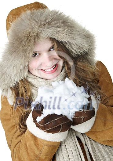 Playful young woman in winter coat with fur hood holding pile of fresh snow