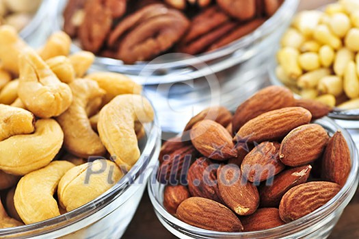 Almonds, cashews pistachio and pine nuts in glass bowls