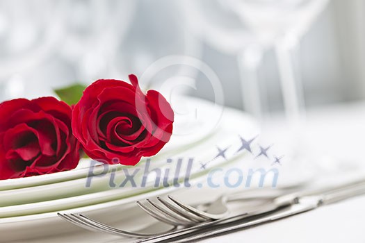 Romantic table setting for two with roses plates and cutlery