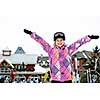 Happy teenage girl with arms raised in ski helmet at winter resort