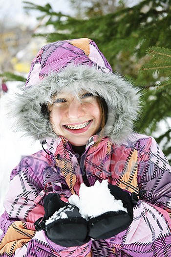 Portrait of happy teenage girl holding snow in gloves