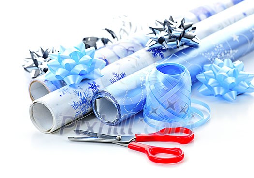 Rolls of Christmas wrapping paper with ribbons, bows and scissors Rolls of Christmas wrapping paper with ribbons, bows and scissors