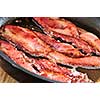 Bacon strips sizzling on a frying pan