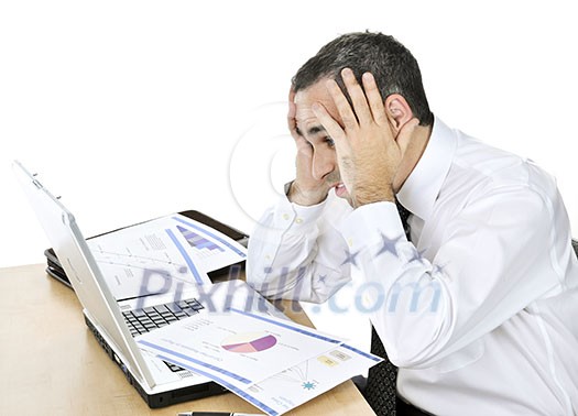 Stressed businessman sitting at his desk isolated on white background