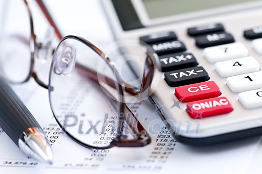 Calculating numbers for income tax return with glasses pen and calculator Calculating numbers for income tax return with glasses pen and calculator