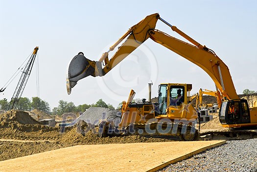 Yellow bulldozer machines digging and moving earth at construction site