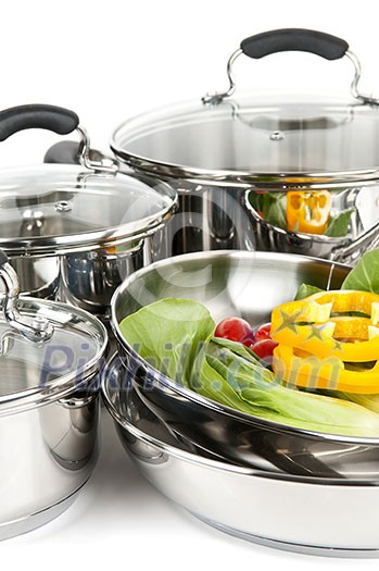 Stainless steel pots and pans isolated on white background with vegetables Stainless steel pots and pans isolated on white background with vegetables