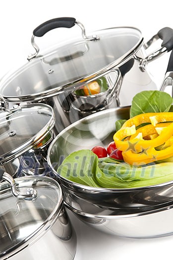 Stainless steel pots and pans isolated on white background with vegetables Stainless steel pots and pans isolated on white background with vegetables
