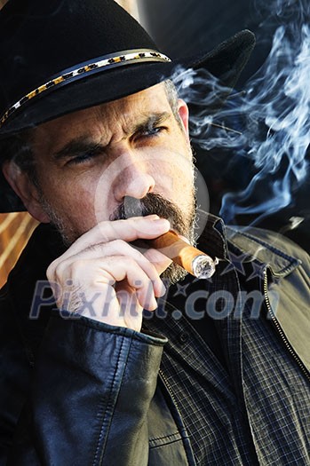 Man with beard in cowboy hat smoking cigar Man with beard in cowboy hat smoking cigar