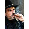 Man with beard in cowboy hat smoking cigar