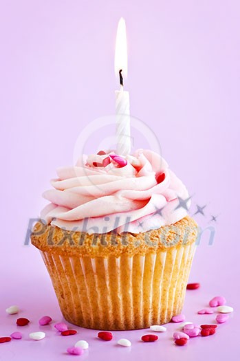 Single cupcake with icing sprinkles and candle Single cupcake with icing sprinkles and candle
