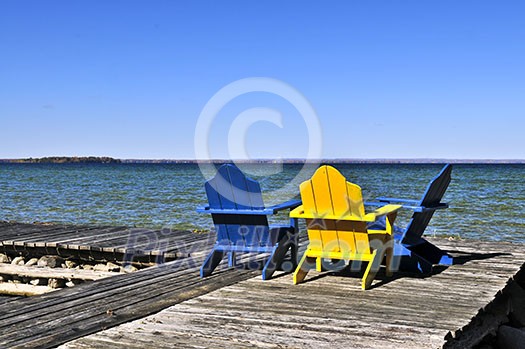 Painted wooden chairs on dock at a lake Painted wooden chairs on dock at a lake