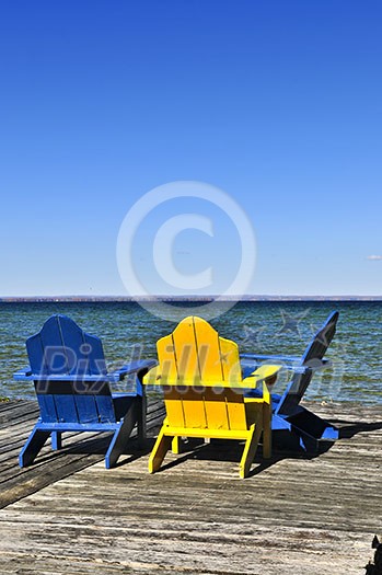Painted wooden chairs on dock at a lake Painted wooden chairs on dock at a lake