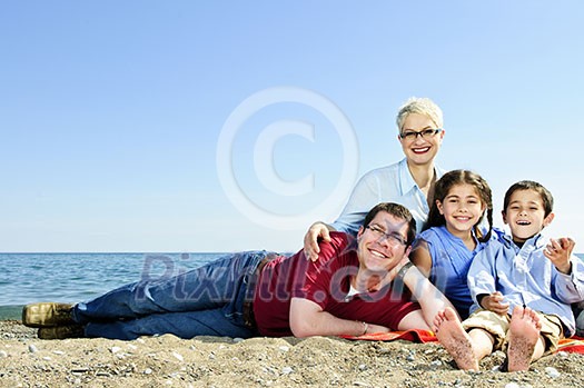 Happy family laying on towel at sandy beach