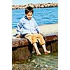Portrait of young boy dipping feet in lake from pier