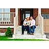 Young family sitting on front steps of house