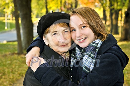 Teen granddaughter hugging grandmother in autumn park Teen granddaughter hugging grandmother in autumn park