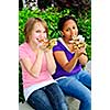 Two teenage girls sitting and eating pizza