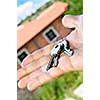 Man's hand holding keys with a house under construction in background