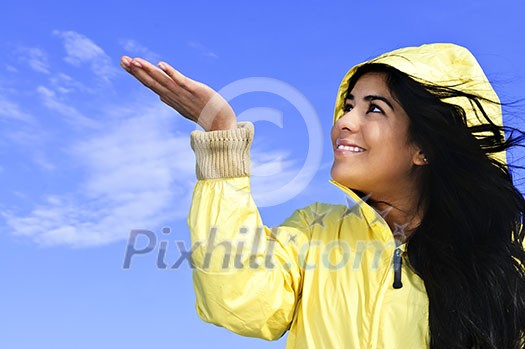Portrait of beautiful smiling girl wearing yellow raincoat looking up checking for rain