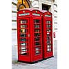 Two red telephone boxes near on London sidewalk