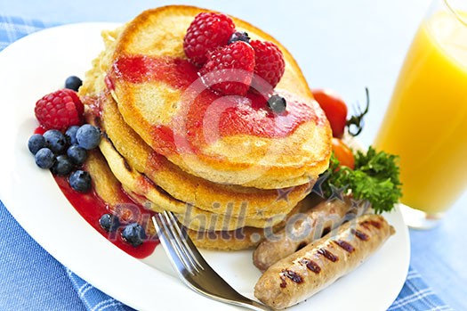 Breakfast of buttermilk pancakes with sausages and fresh berries