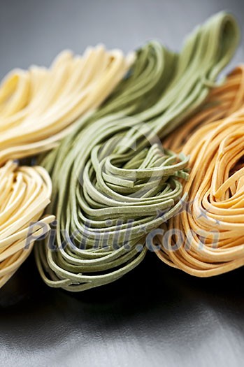 Assorted bundles of colorful raw tagliolini pasta noodles Assorted bundles of colorful raw tagliolini pasta noodles
