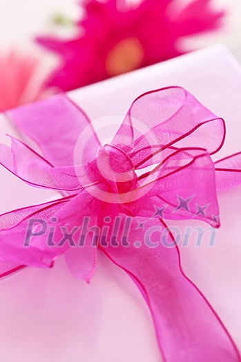 Gift box wrapped in pink paper with ribbon and bow