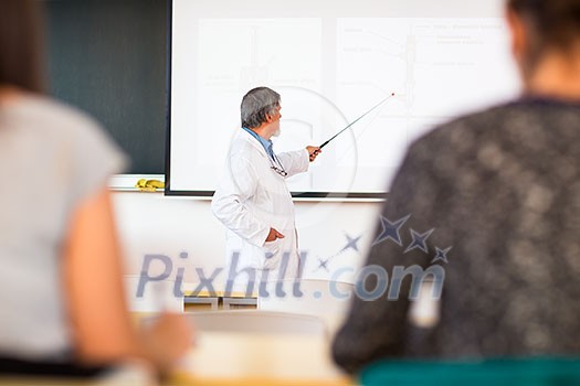 Senior chemistry professor giving a lecture in front of classroom full of students (shallow DOF; color toned image) Senior chemistry professor giving a lecture in front of classroom full of students (shallow DOF; color toned image)