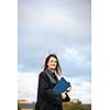 Pretty, young woman celebrating joyfully her graduation - spreading wide her arms, holding her diploma, savouring her success (color toned image; shallow DOF)