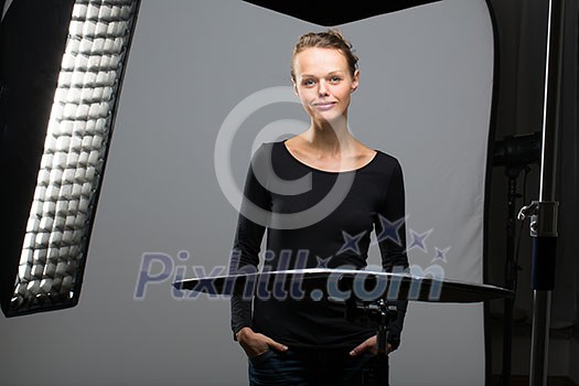 Beautiful female model posing in a photographic studio surrounded by professional strobe lights