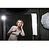 Beautiful female model posing in a photographic studio surrounded by professional strobe lights