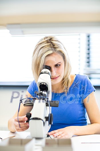 Pretty, young female optician/optometrist measuring new glasses she has prepared for a customer