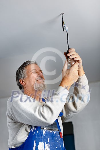 Senior man installing a bulb in a freshly renovated appartment Senior man installing a bulb in a freshly renovated appartment
