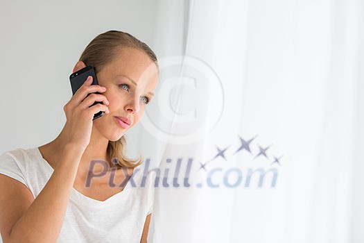 Pretty, young woman calling on her call phone, pensive, concentrating, wearing bright clothes inside a modern, fresh interior (color toned image; shallow DOF) Pretty, young woman calling on her call phone, pensive, concentrating, wearing bright clothes inside a modern, fresh interior (color toned image; shallow DOF)