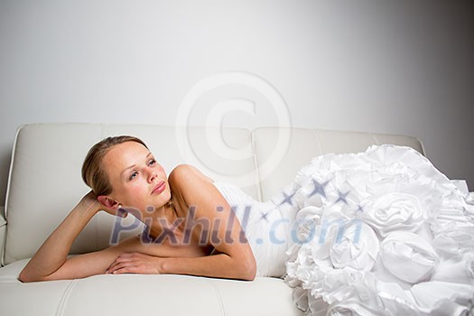 Beautiful bride lying on a sofa, looking pensive Beautiful bride lying on a sofa, looking pensive