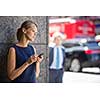 Pretty, young businesswoman talking on the phone in front of a modern building in Manhattan (shallow DOF; color toned image)