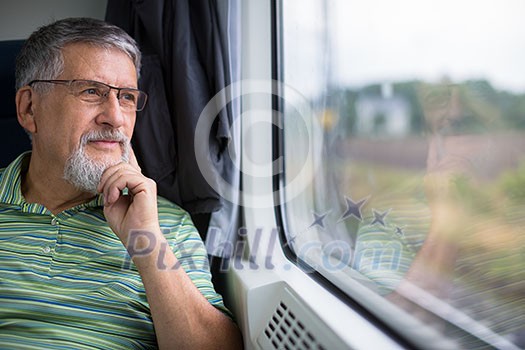 Senior man enjoying a train travel - leaving his car at home, he savours the time spent travelling, looks out of the window, has time to admire the landscape passing by