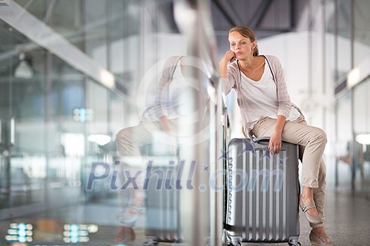 Young female passenger at the airport, waiting for her delayed flight