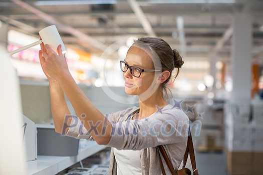 Pretty, young woman choosing the right light for her appartment in a modern home furnishings store (color toned image; shallow DOF) Pretty, young woman choosing the right light for her appartment in a modern home furnishings store (color toned image; shallow DOF)