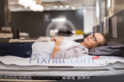 Pretty, young woman choosing the right furniture for her apartment in a modern home furnishings store (color toned image; shallow DOF)