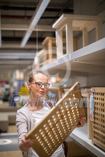 Pretty, young woman choosing the right furniture for her apartment in a modern home furnishings store (color toned image; shallow DOF)