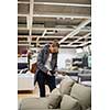 Pretty, young woman choosing the right furniture for her apartment in a modern home furnishings store (color toned image; shallow DOF)
