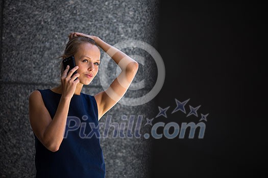 Pretty, young businesswoman talking on the phone in front of a modern building in Manhattan (shallow DOF; color toned image)