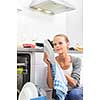 Young woman washing dishes in her modern kitchen, using a dishwasher, putting the dishes in their place