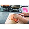 Young woman seasoning a salmon filet in her modern kitchen, preaparing a healthy food