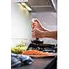 Young woman seasoning a salmon filet in her modern kitchen, preaparing a healthy food