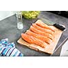 Young woman seasoning a salmon filet in her modern kitchen, preaparing a healthy food