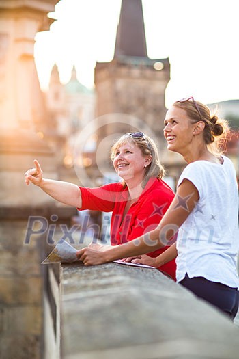 Mother and daughter traveling - two female tourists studying a map, discovering a new city