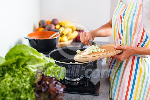 Young woman cooking in her modern kitchen (shallow DOF; color toned image)